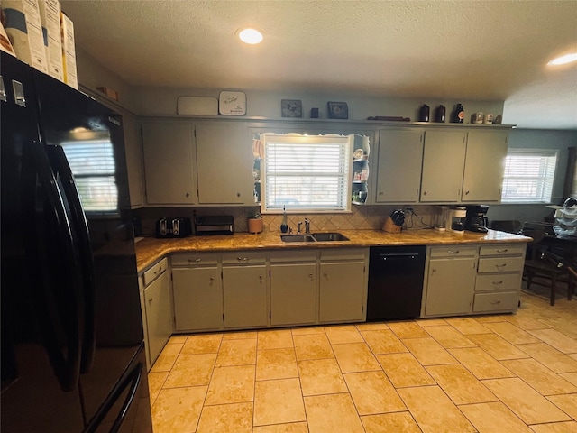 kitchen with light tile patterned flooring, sink, black appliances, a textured ceiling, and backsplash