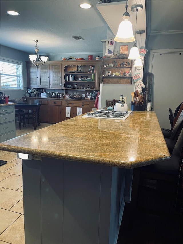 kitchen featuring tile patterned flooring, hanging light fixtures, kitchen peninsula, and stainless steel gas stovetop