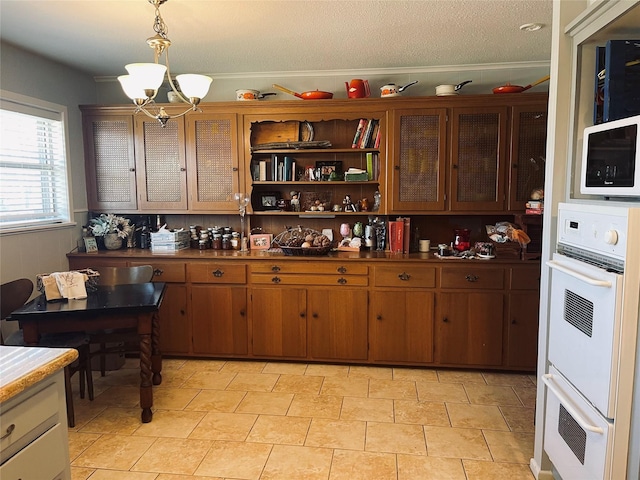 kitchen with white double oven, a chandelier, hanging light fixtures, and a textured ceiling