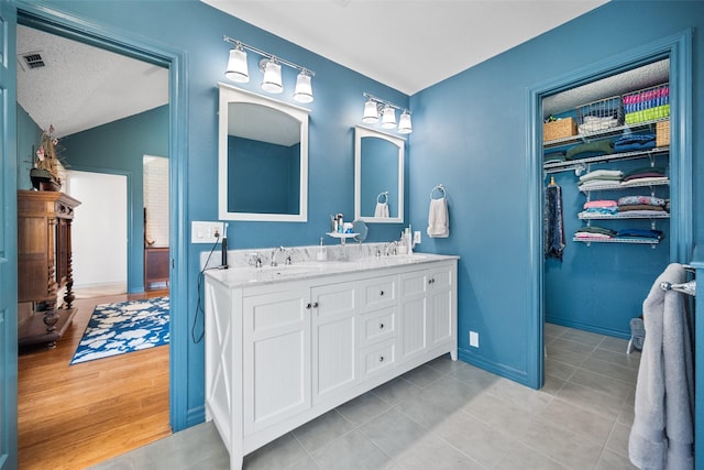 bathroom with tile patterned floors, lofted ceiling, vanity, and a textured ceiling