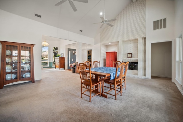 carpeted dining area featuring ceiling fan, a fireplace, and high vaulted ceiling