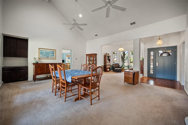 carpeted dining space with ceiling fan, high vaulted ceiling, and decorative columns