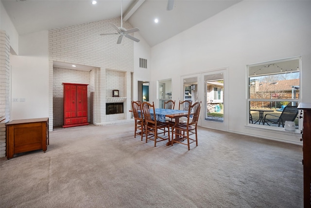 carpeted dining area featuring beamed ceiling, ceiling fan, high vaulted ceiling, and a fireplace