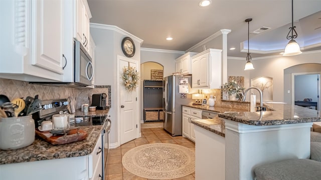 kitchen featuring pendant lighting, sink, appliances with stainless steel finishes, white cabinetry, and dark stone countertops