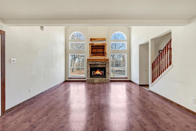 unfurnished living room featuring a stone fireplace and dark hardwood / wood-style flooring