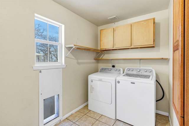 laundry area featuring light tile patterned floors, cabinets, and washing machine and clothes dryer