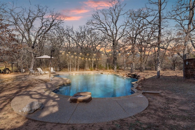 pool at dusk featuring a patio