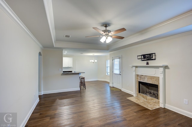 unfurnished living room featuring ornamental molding, a tray ceiling, dark hardwood / wood-style flooring, and a tile fireplace