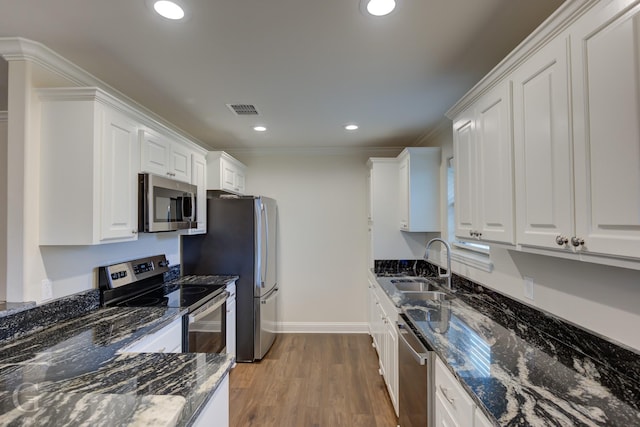 kitchen with sink, hardwood / wood-style floors, stainless steel appliances, white cabinets, and dark stone counters