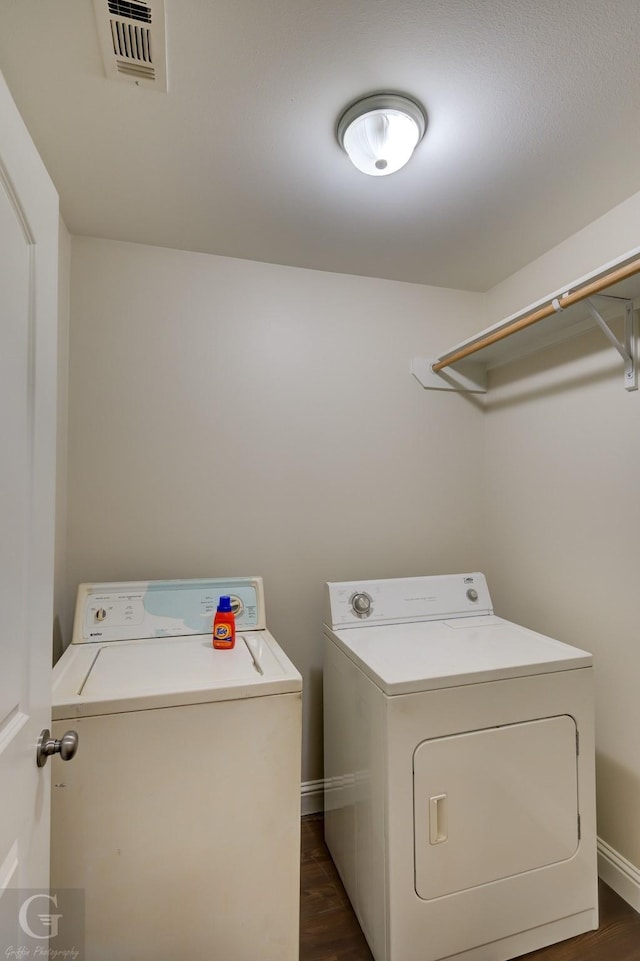 clothes washing area with washing machine and clothes dryer and dark hardwood / wood-style flooring