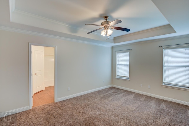 spare room with ceiling fan, light colored carpet, ornamental molding, and a tray ceiling