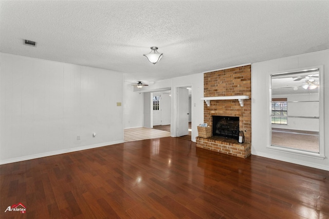 unfurnished living room with a fireplace, ceiling fan, wood-type flooring, and a textured ceiling