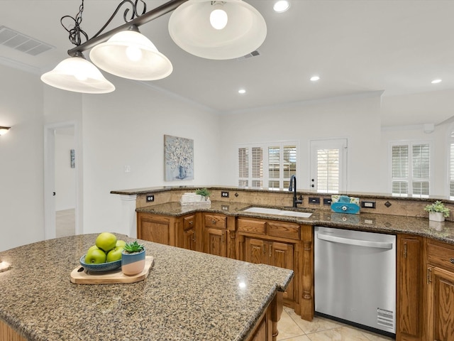 kitchen with sink, dishwasher, dark stone countertops, a kitchen island, and decorative light fixtures