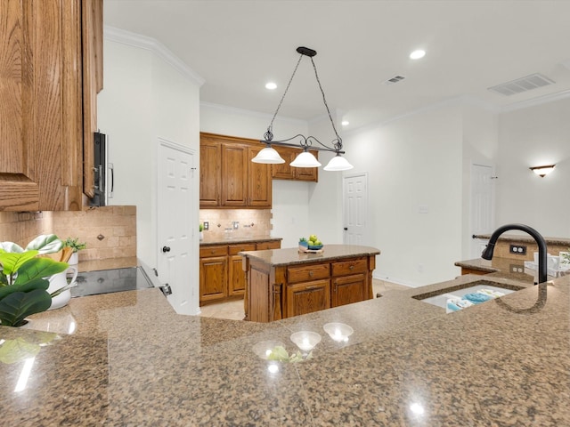 kitchen with sink, crown molding, decorative light fixtures, a center island, and stone counters