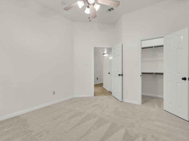 unfurnished bedroom with a spacious closet, light carpet, ceiling fan, and a closet