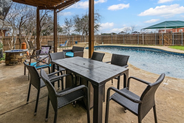 view of pool featuring a patio, an outdoor fire pit, outdoor dining space, and a fenced backyard