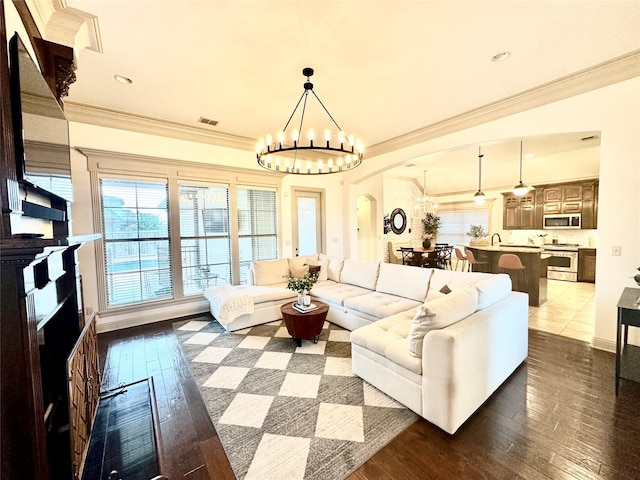 living room featuring dark wood-type flooring, ornamental molding, and a notable chandelier