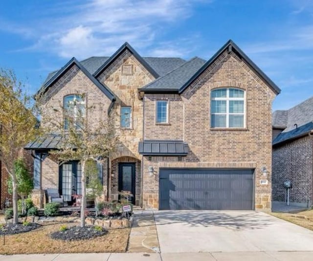 view of front of property with driveway, stone siding, an attached garage, a standing seam roof, and brick siding