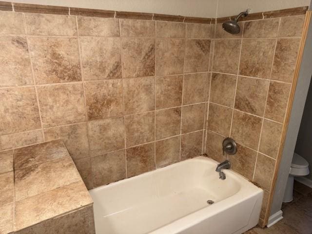 bathroom featuring tiled shower / bath and toilet