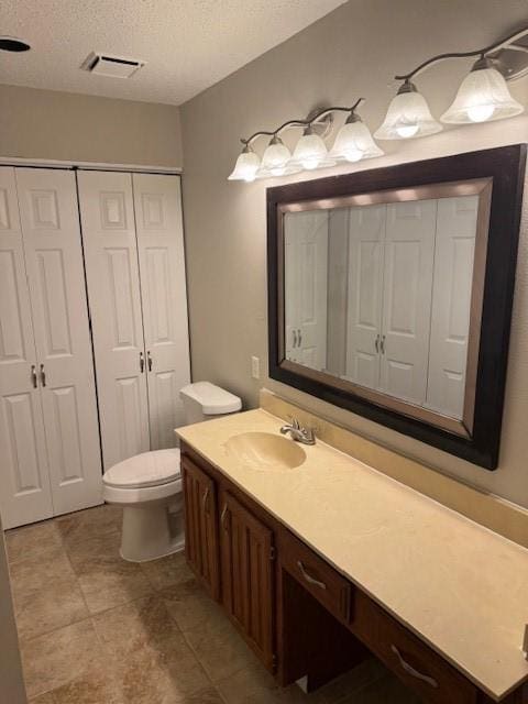 bathroom featuring vanity, toilet, and a textured ceiling