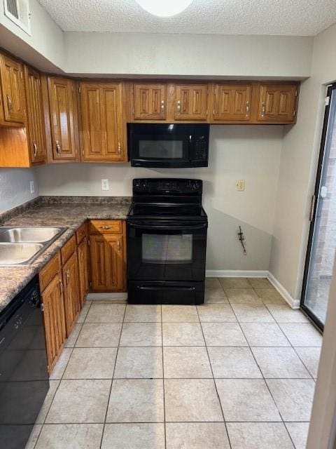 kitchen with light tile patterned floors, black appliances, and a textured ceiling