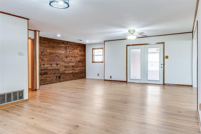 unfurnished room featuring ceiling fan, wooden walls, and light hardwood / wood-style floors