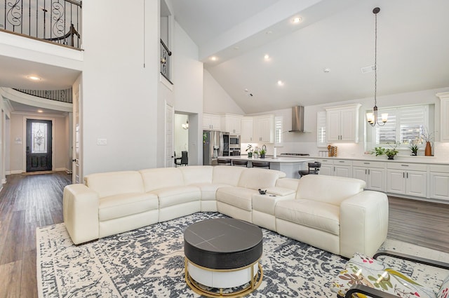 living room with a notable chandelier, high vaulted ceiling, and light wood-type flooring