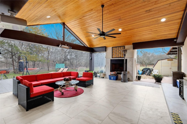 view of patio with an outdoor living space with a fireplace, ceiling fan, and a storage unit