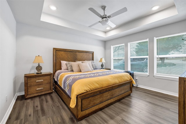 bedroom featuring a tray ceiling, dark wood-type flooring, and ceiling fan