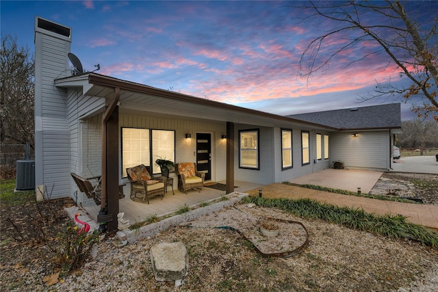 back house at dusk with central AC and a patio