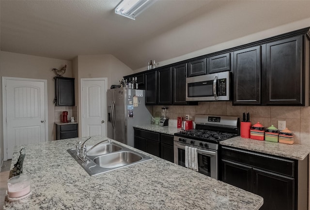 kitchen featuring an island with sink, appliances with stainless steel finishes, sink, and backsplash