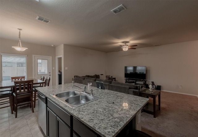 kitchen with decorative light fixtures, an island with sink, sink, stainless steel dishwasher, and ceiling fan