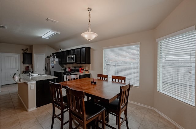 dining space featuring lofted ceiling, sink, and light tile patterned floors