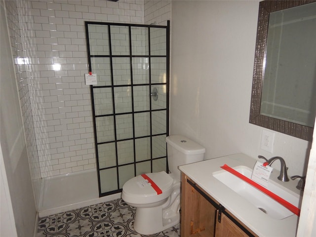 bathroom featuring vanity, tiled shower, tile patterned floors, and toilet