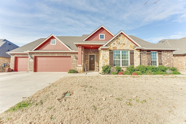 craftsman house featuring an attached garage, brick siding, driveway, stone siding, and roof with shingles