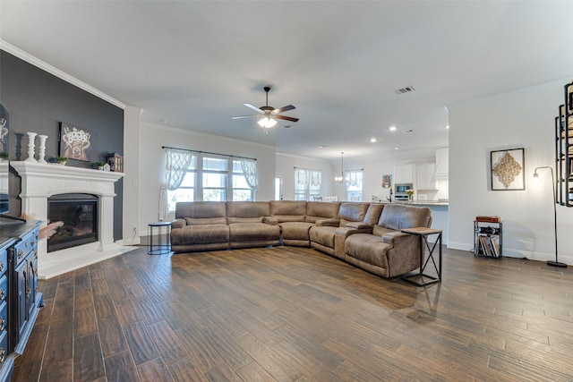 living room featuring dark wood-type flooring, ceiling fan, and crown molding