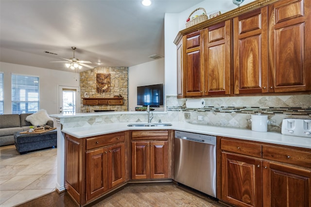 kitchen with tasteful backsplash, stainless steel dishwasher, a fireplace, sink, and kitchen peninsula