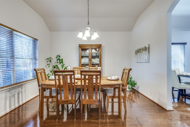 dining space featuring vaulted ceiling, a notable chandelier, plenty of natural light, and wood-type flooring