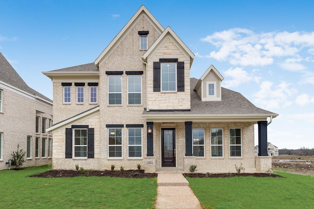 view of front of property with a front yard, stone siding, and roof with shingles