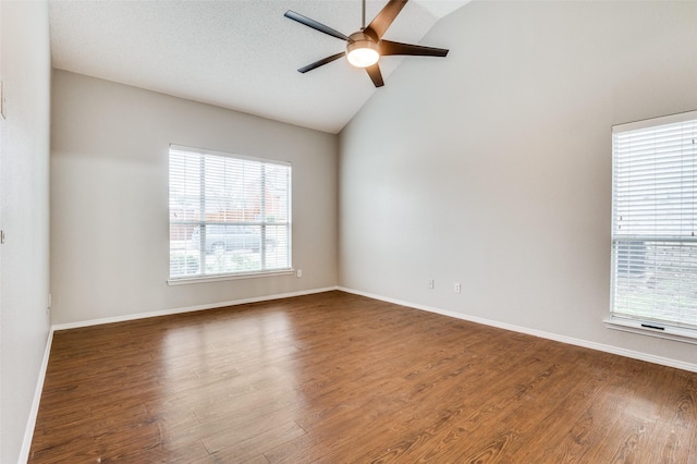 unfurnished room with ceiling fan, a healthy amount of sunlight, dark hardwood / wood-style floors, and vaulted ceiling