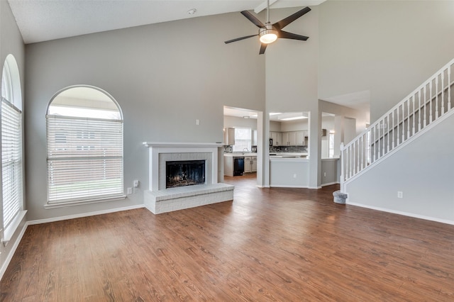 unfurnished living room with a brick fireplace, hardwood / wood-style floors, and ceiling fan