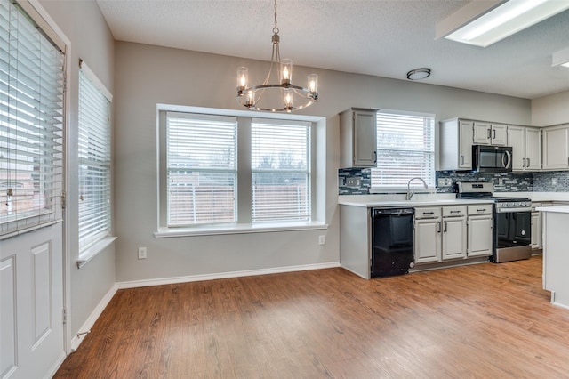 kitchen with pendant lighting, dishwasher, tasteful backsplash, stainless steel range oven, and light wood-type flooring