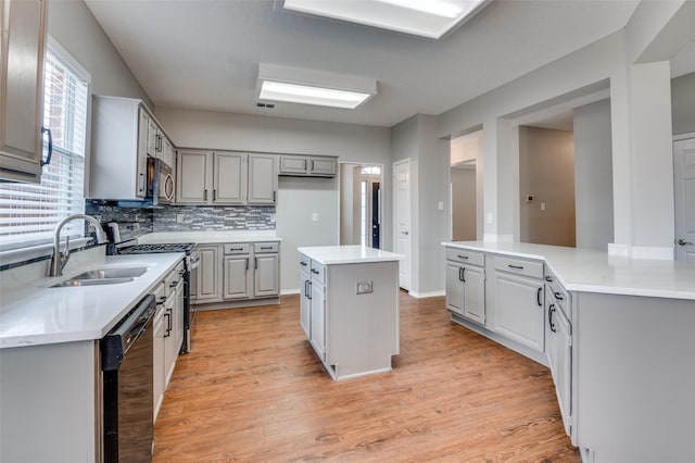 kitchen featuring appliances with stainless steel finishes, sink, gray cabinetry, a center island, and light hardwood / wood-style floors