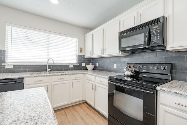 kitchen featuring sink, light hardwood / wood-style flooring, white cabinetry, light stone counters, and black appliances