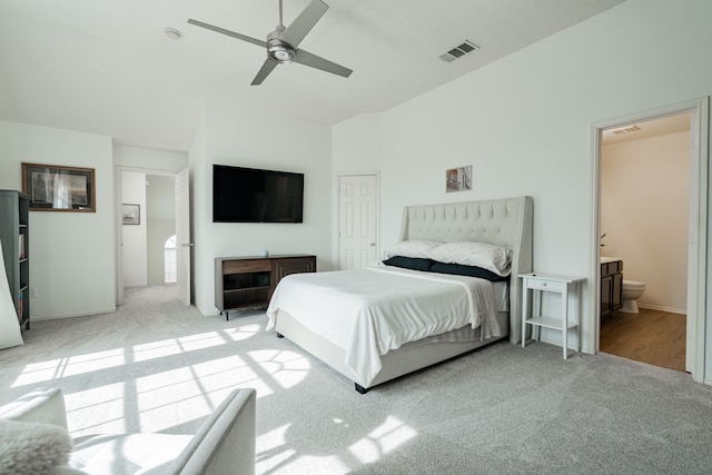 carpeted bedroom with vaulted ceiling, ceiling fan, and ensuite bath