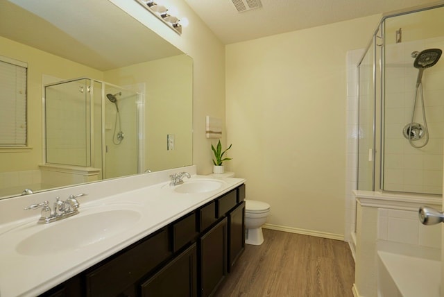 bathroom featuring walk in shower, vanity, toilet, and hardwood / wood-style floors