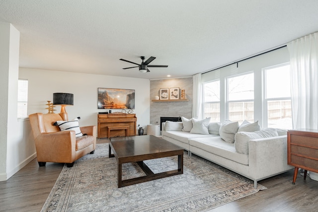 living room with hardwood / wood-style floors, a large fireplace, a textured ceiling, and ceiling fan