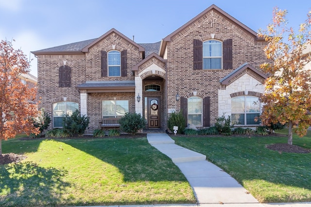 french country inspired facade with stone siding, brick siding, and a front yard