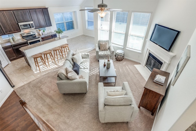 living room with baseboards, a fireplace with flush hearth, and a ceiling fan