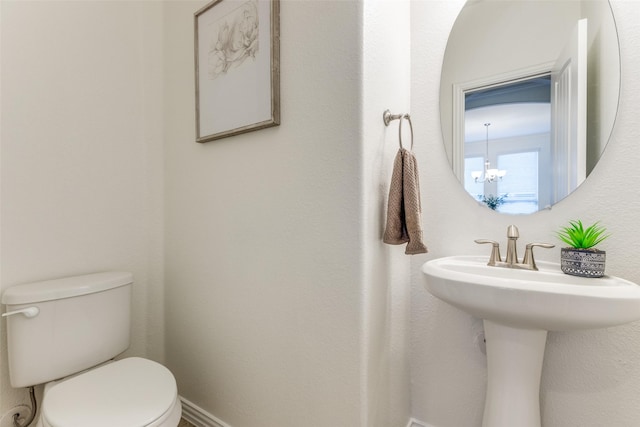 bathroom featuring toilet and an inviting chandelier